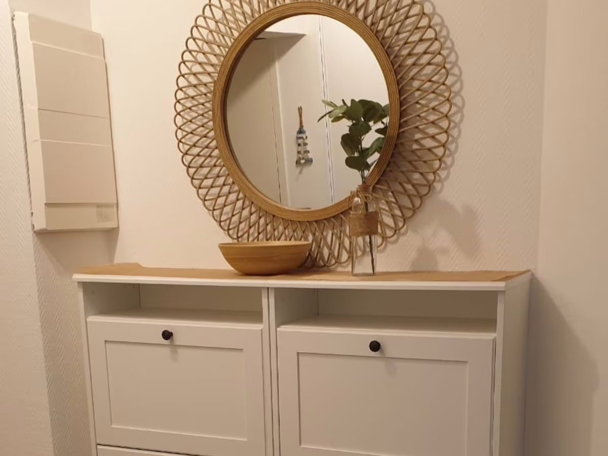 Meuble à chaussures et miroir en rotin Meuble blanc avec miroir rond en rotin et petit vase végétal - consultante en aménagement intérieur en gironde
